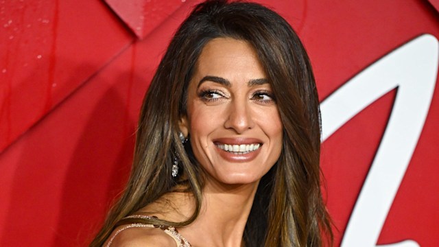 Amal Clooney in a gold dress looking to her right at The Fashion Awards 2023 