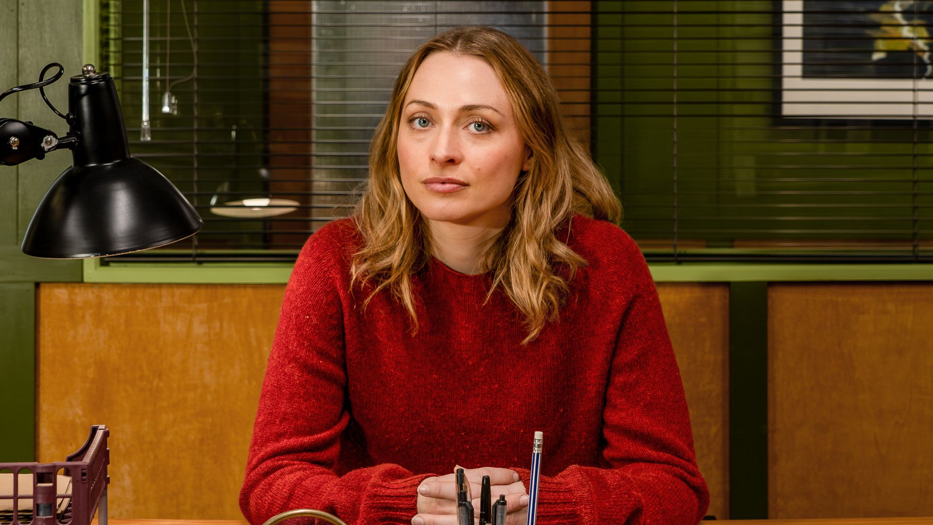 blonde woman in red jumper sitting in office