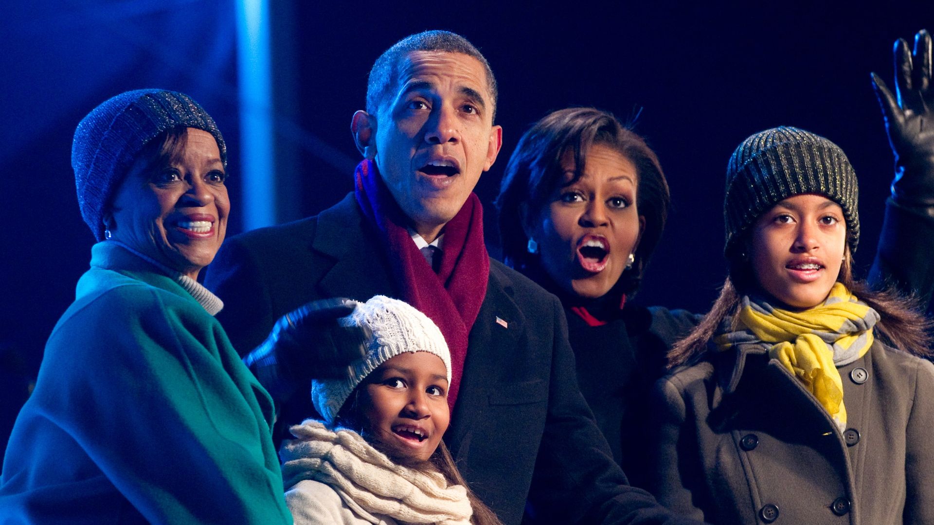 US President Barack Obama, joined by his family including First Lady Michelle Obama, daughters Sasha and Malia, and mother-in-law Marian Robinson, react as they push a button to light the National Christmas Tree during a ceremony on the Ellipse near the White House in Washington, DC, December 9, 2010.