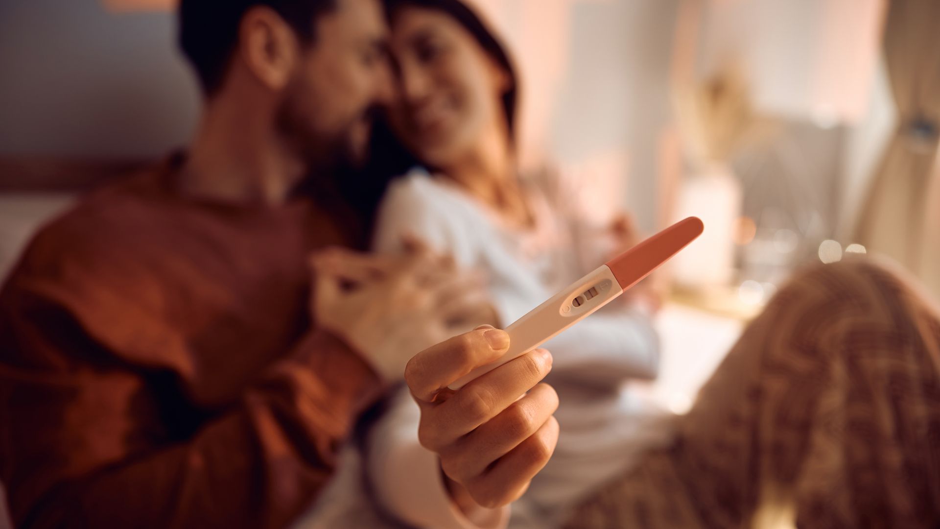 Close up of couple with positive pregnancy test.