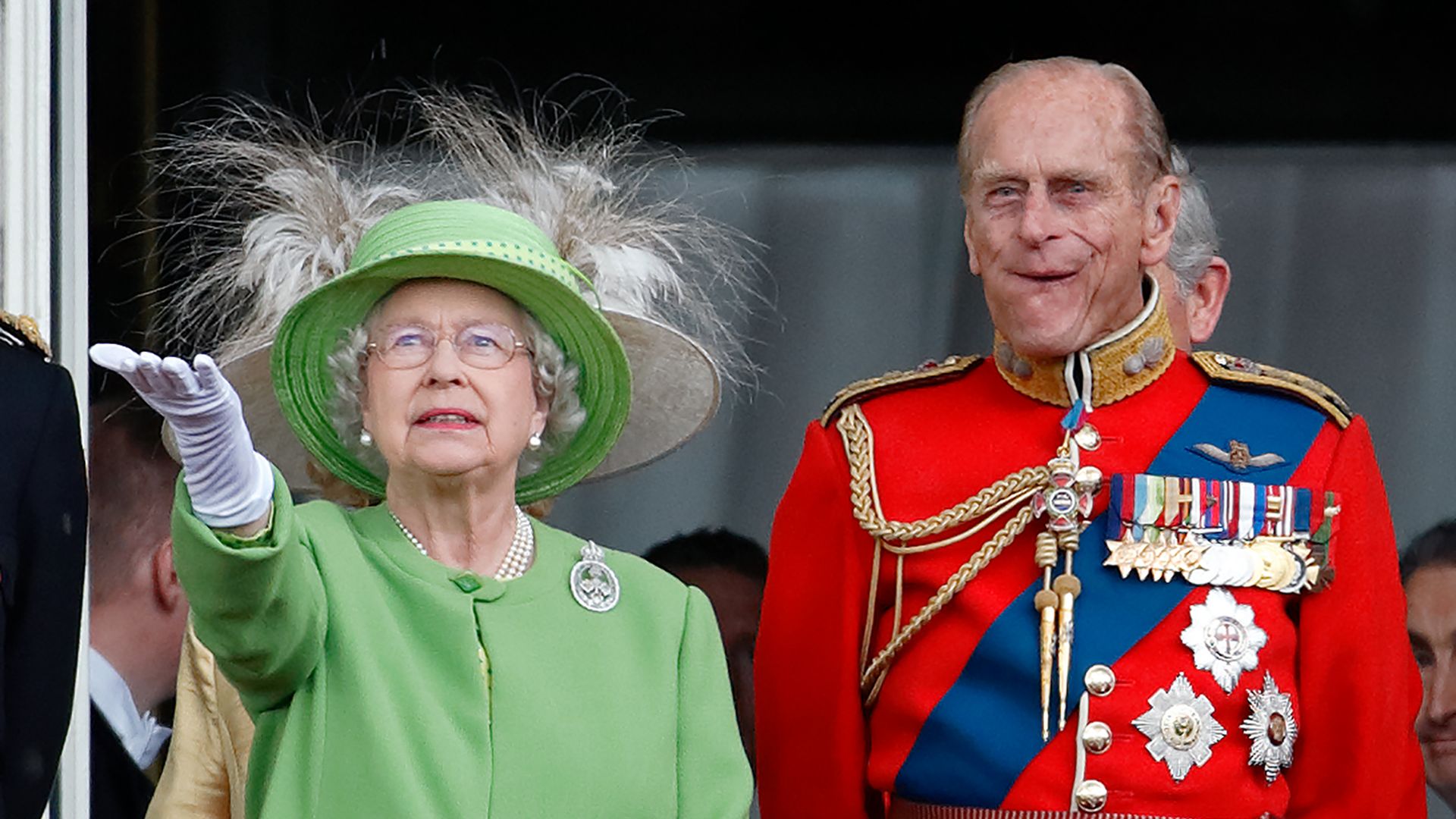 The Queen holding her hand out to check for rain stood next to Prince Philip