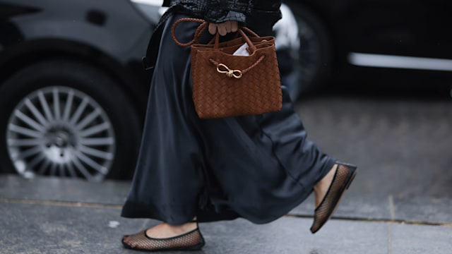 Woman wearing mesh ballet flats and woven bag 