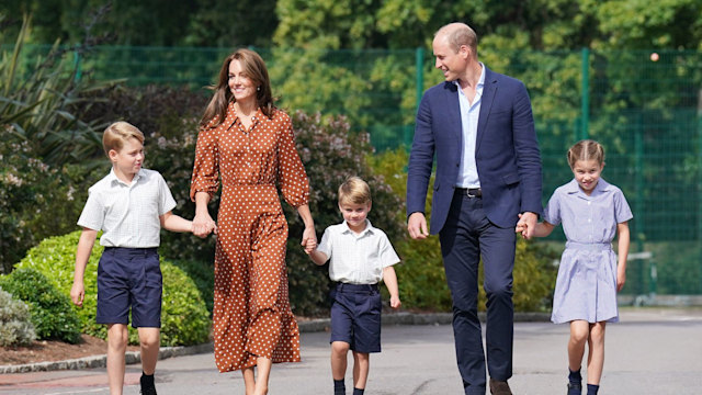 Prince George, Kate Middleton, Prince Louis, Prince William and Princess Charlotte walking towards a school