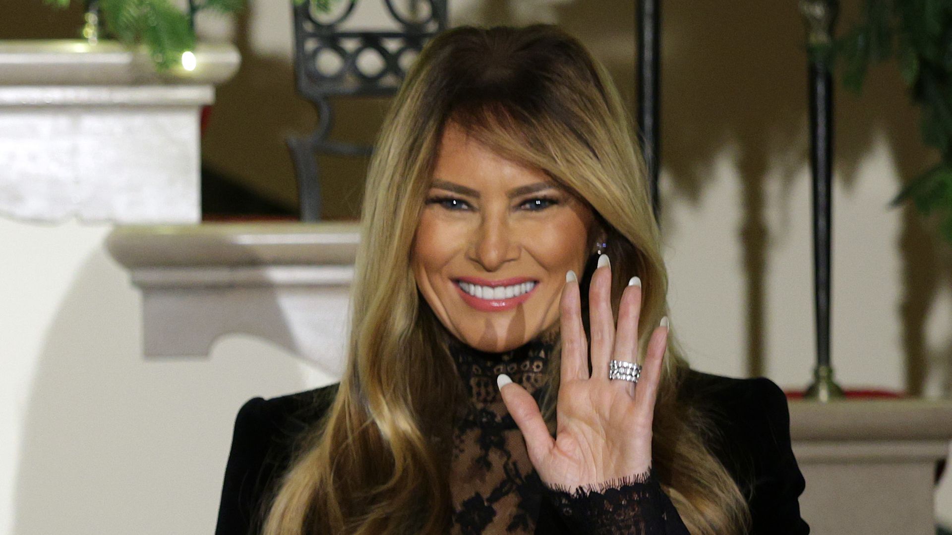 President Donald Trump in tuxedo and First Lady Melania Trump in lace blouse wave to attendees during the Congressional Ball at the Grand Foyer of the White House