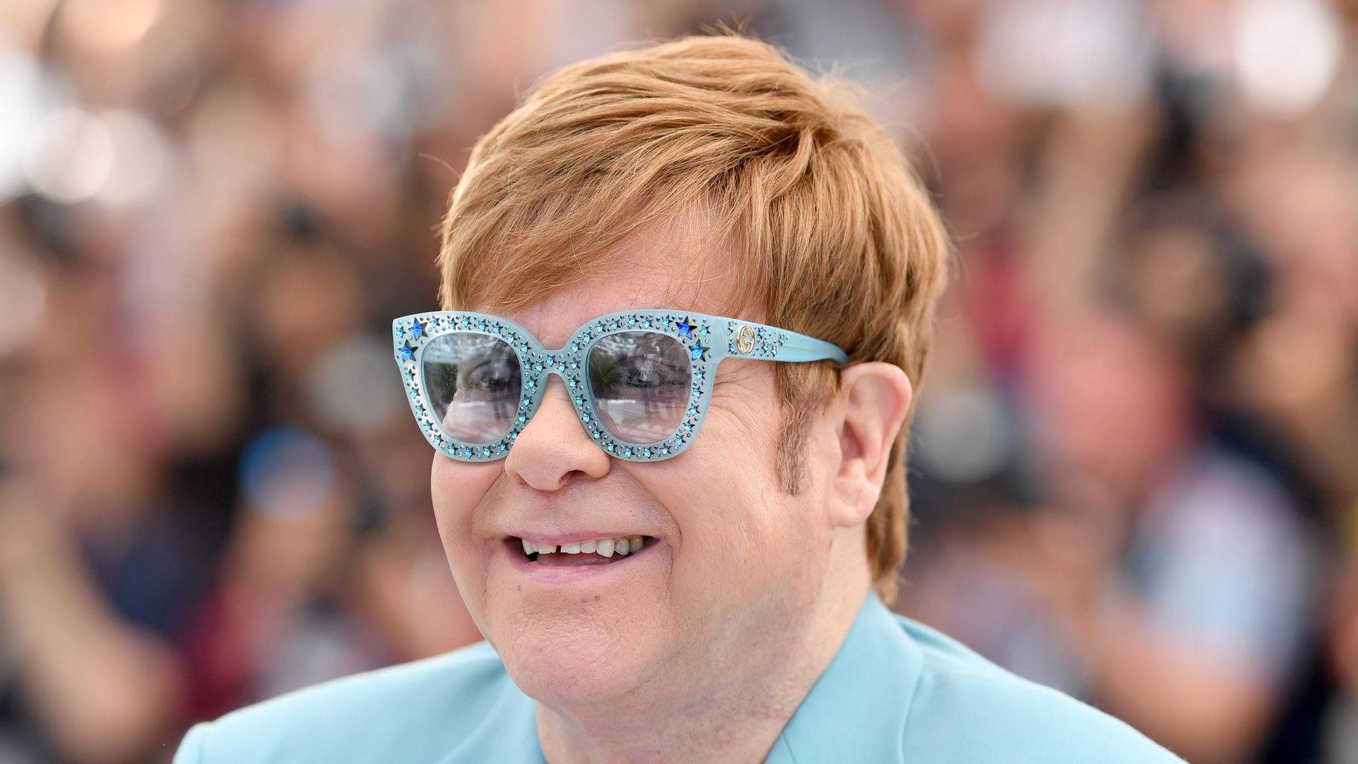 Elton John wearing a blue suit and blue glasses 
