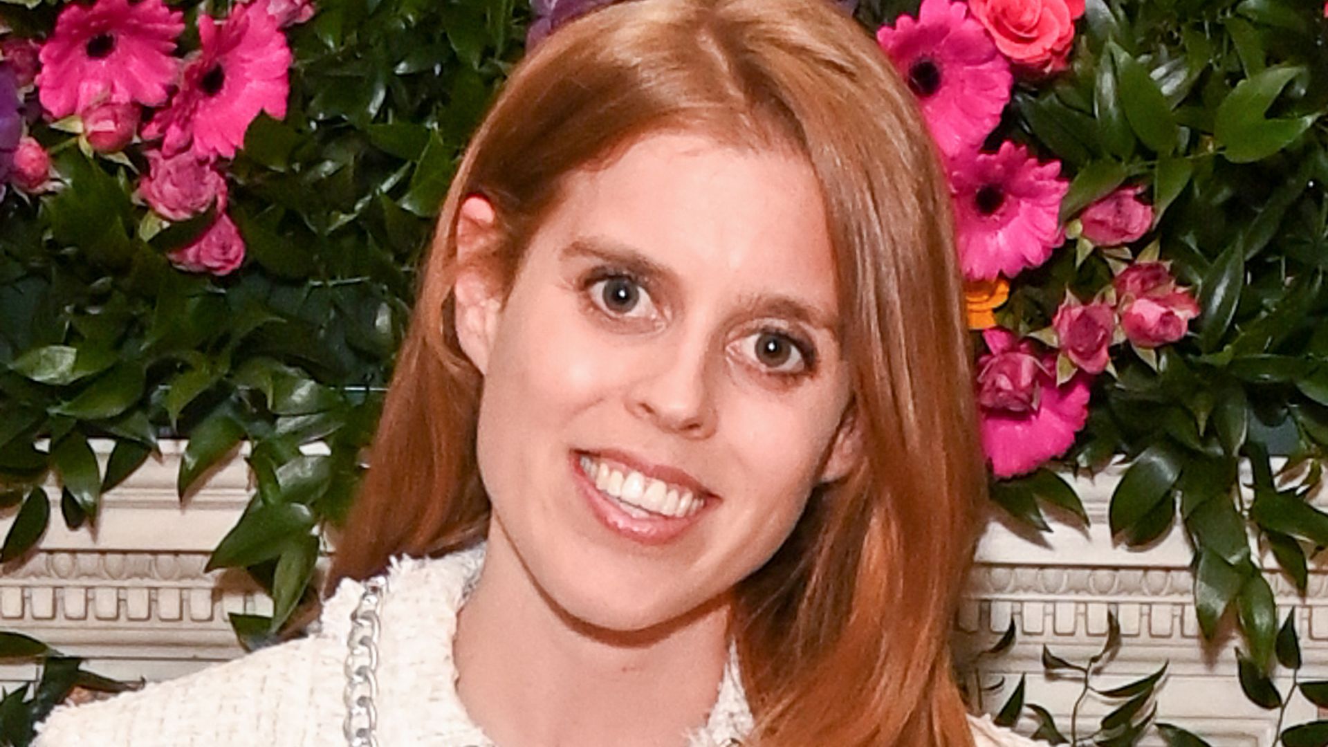 Princess Beatrice in a white skirt against a backdrop of flowers