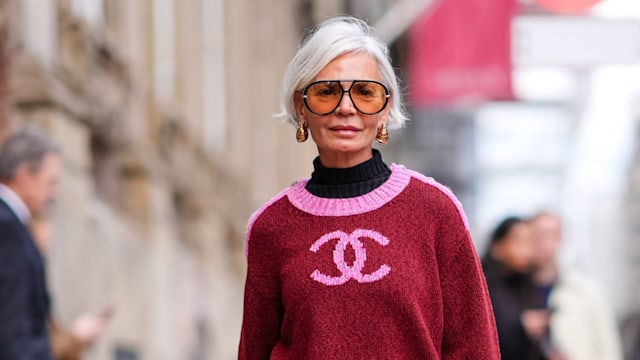 Grece Ghanem wears sunglasses, golden earrings, a black turtleneck pullover , a pink and red Chanel pullover, a red midi checkered / checked pattern printed skirt , burgundy leggings, matching leather shoes, a Hermes pink bag, outside The Garment, during the Copenhagen Fashion Week AW24 on January 31, 2024 in Copenhagen, Denmark