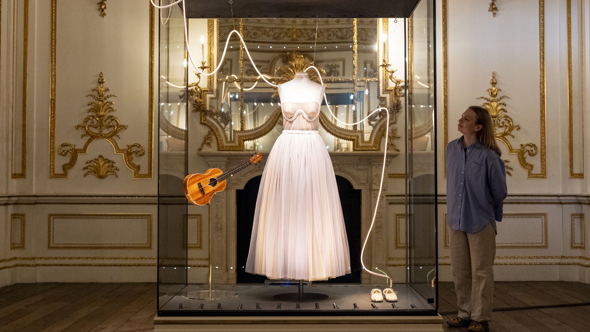 A gallery assistant looks at the outfit worn by Taylor Swift on the Speak Now (Taylor's Version) back album cover during a photo call for the Taylor Swift Songbook Trail, at the Victoria and Albert Museum (V&A) in South Kensington, London. The free temporary trail features 13 installations that celebrate the creative process and career of 14-time Grammy Award winning artist, Taylor Swift. Picture date: Wednesday July 24, 2024. (Photo by Jordan Pettitt/PA Images via Getty Images)
