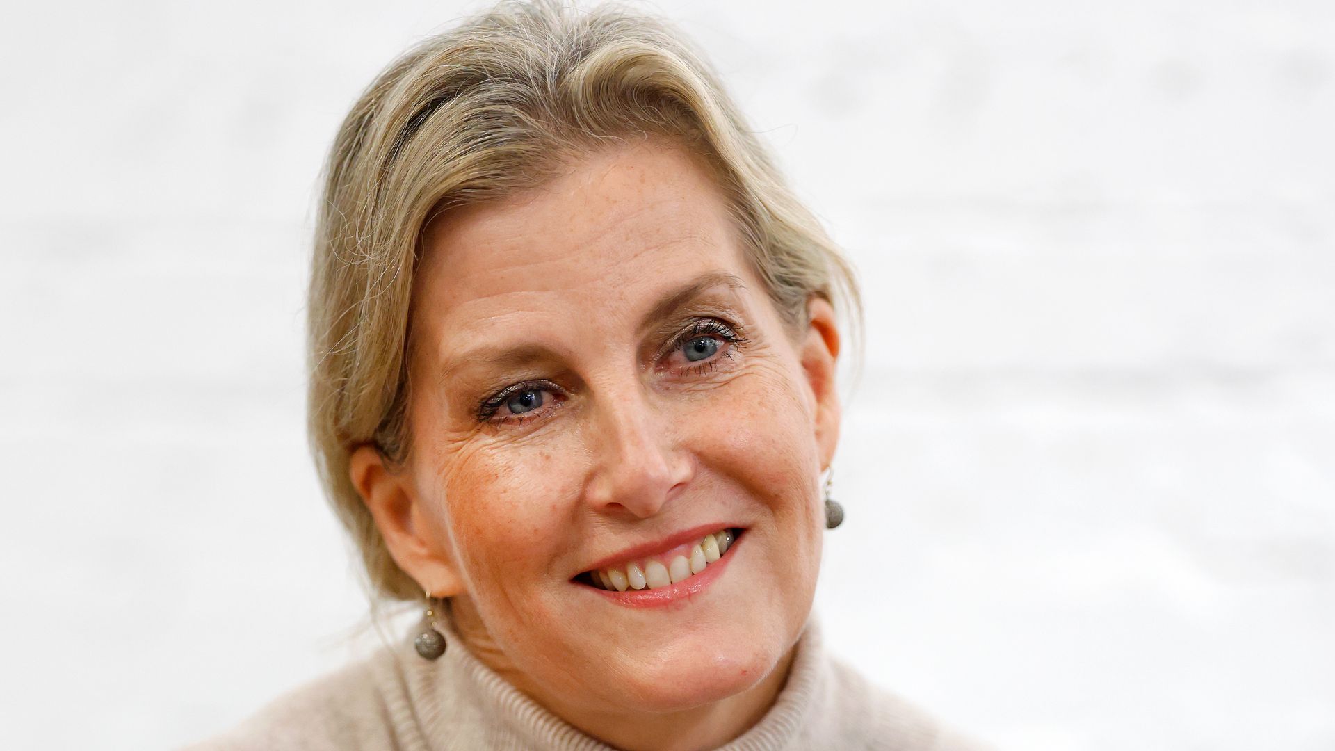 Sophie, Duchess of Edinburgh smiling up close in rollneck oatmeal dress