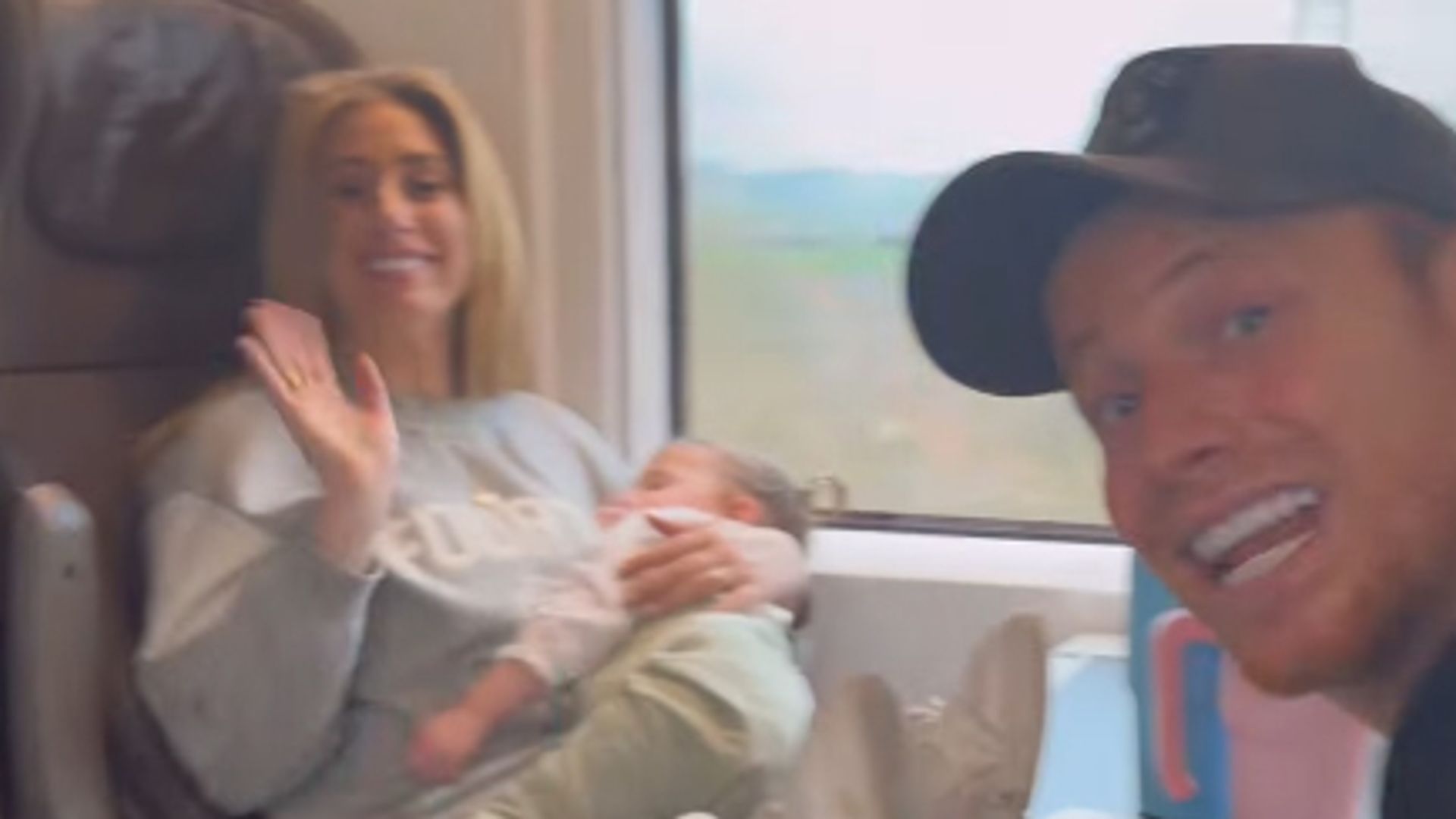 Stacey Solomon holding a baby while on a train with Joe Swash