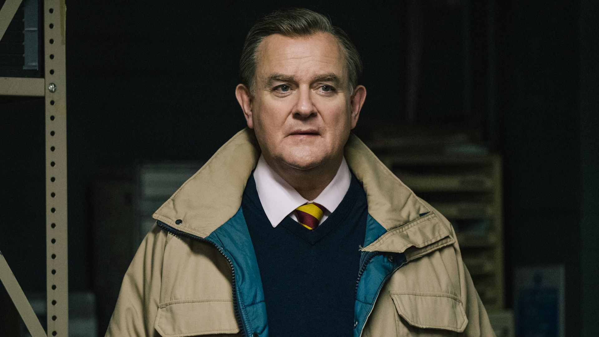 man in jacket standing in dark room