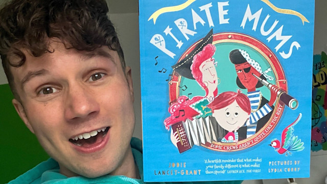 Olly Pike holding up a copy of The Pirate Mums