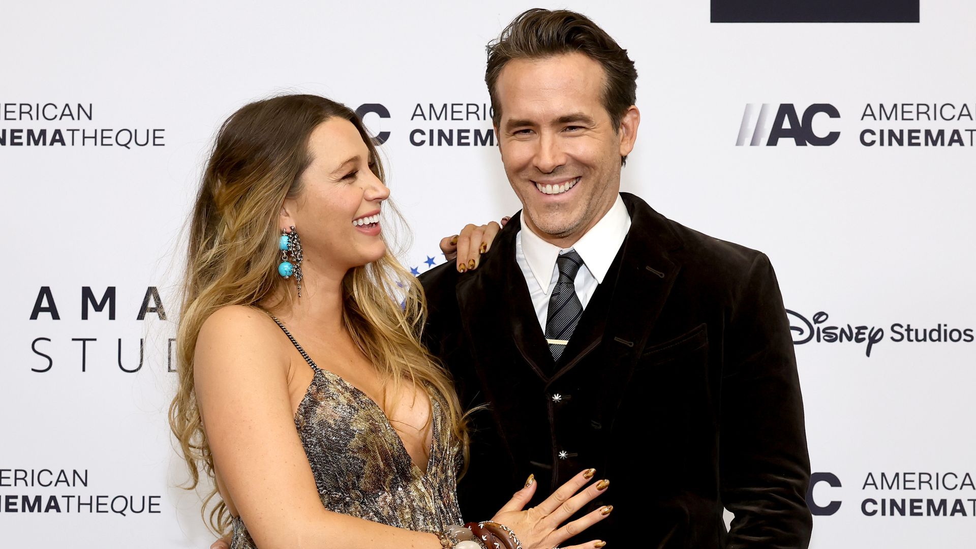 Ryan Reynolds and a pregnant Blake Lively smiling at each other