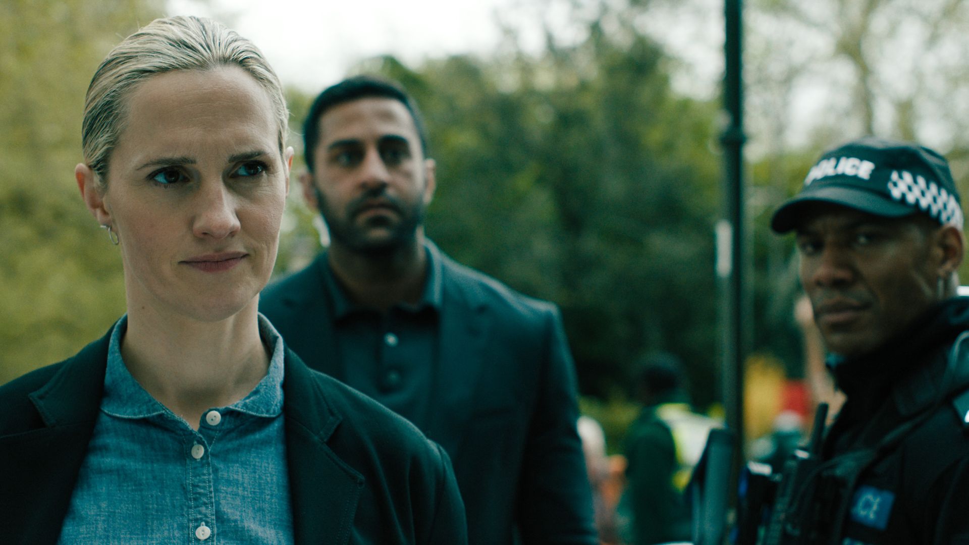 A woman stands in front of two police officers