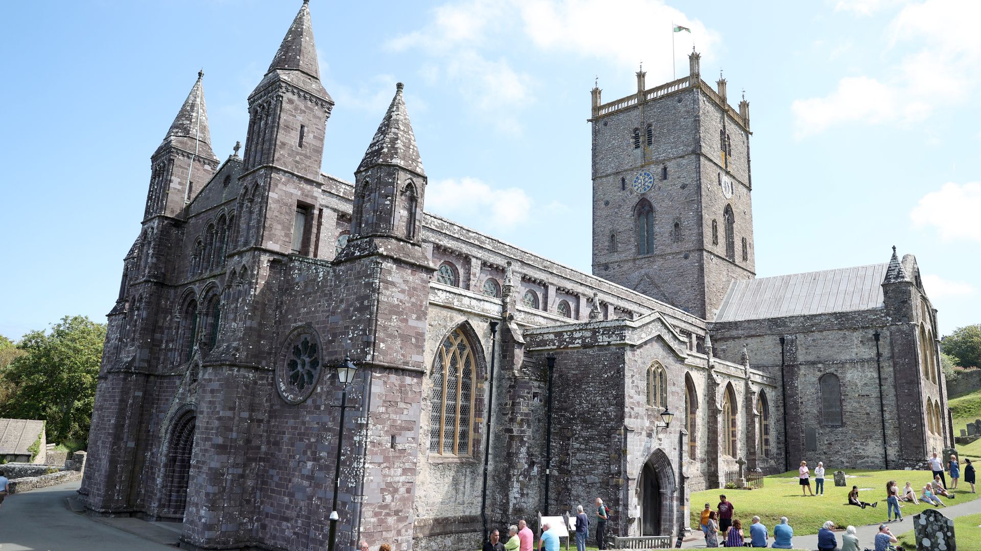 An image of St Davids Cathedral with people sitting outside