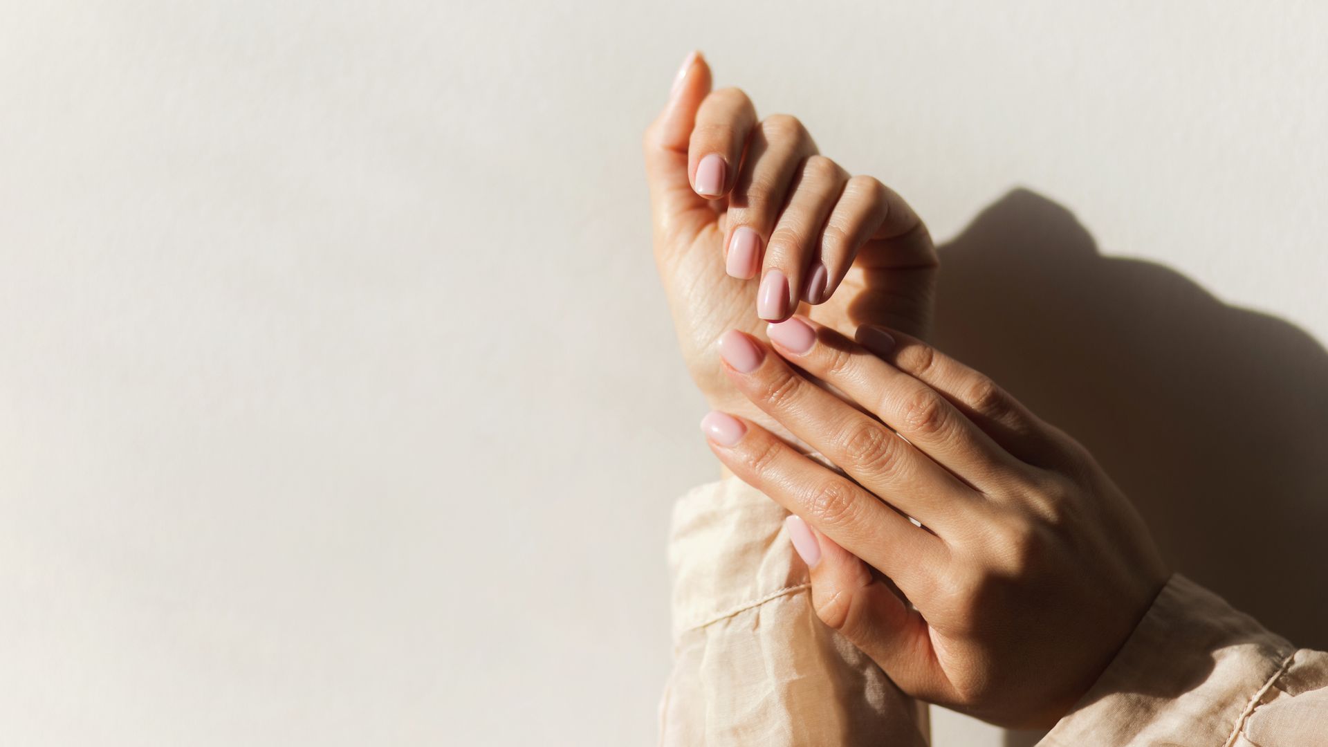 Manicure on female hands with light pink nail polish.