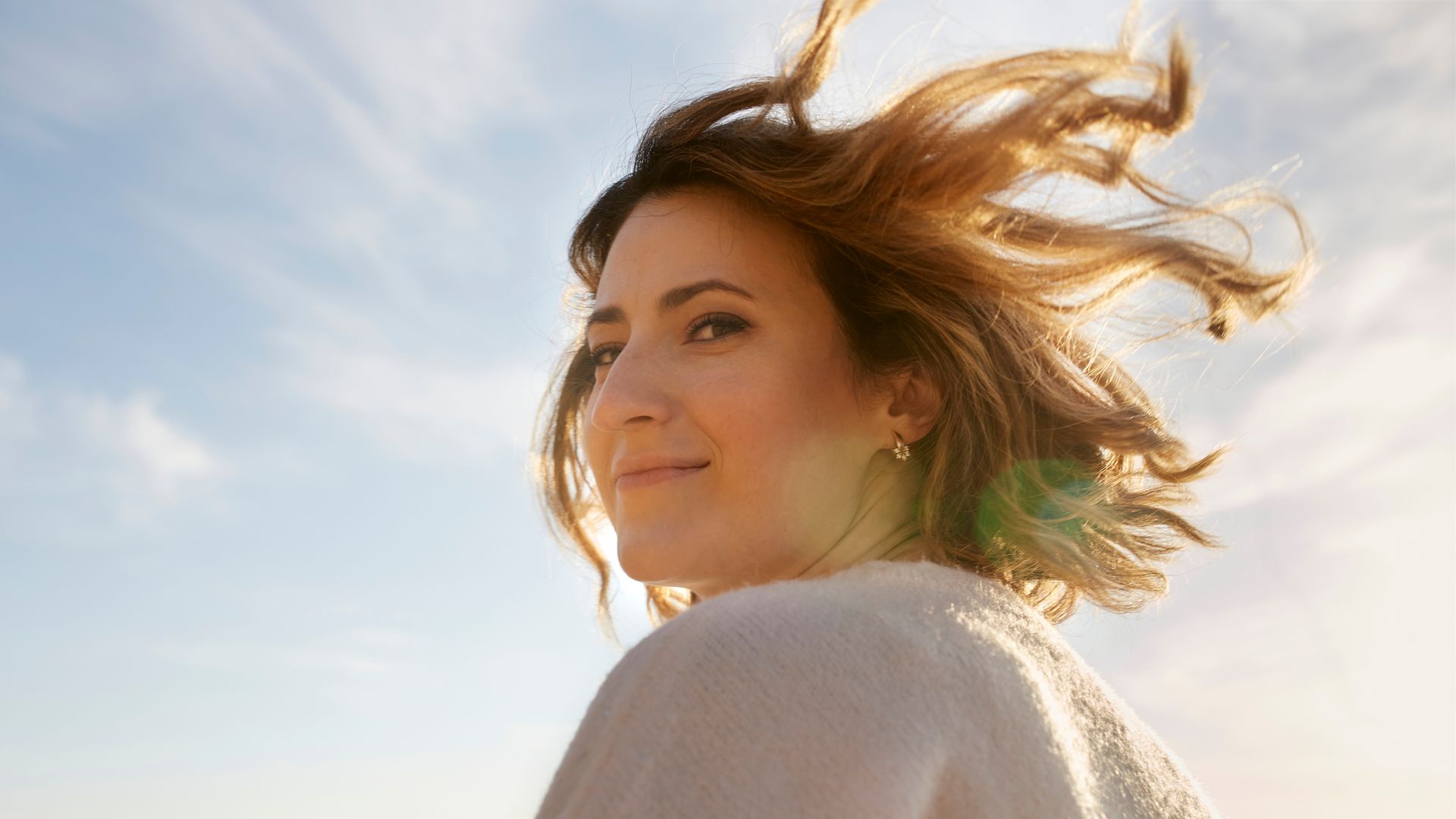 Portrait of smiling woman with tousled hair at sunset