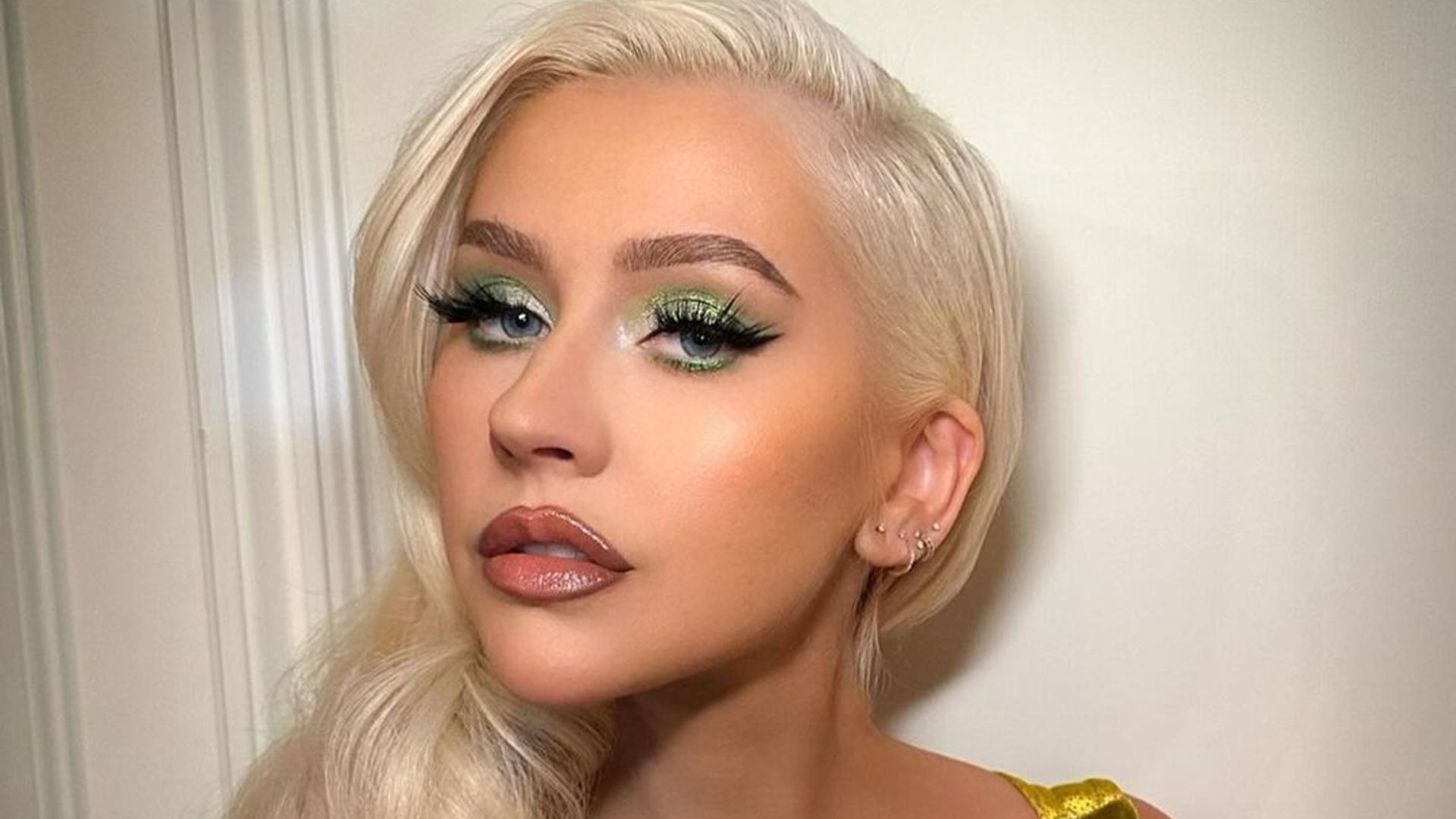 Christina Aguilera in yellow dress with platinum blonde hair and green eyeshadow
