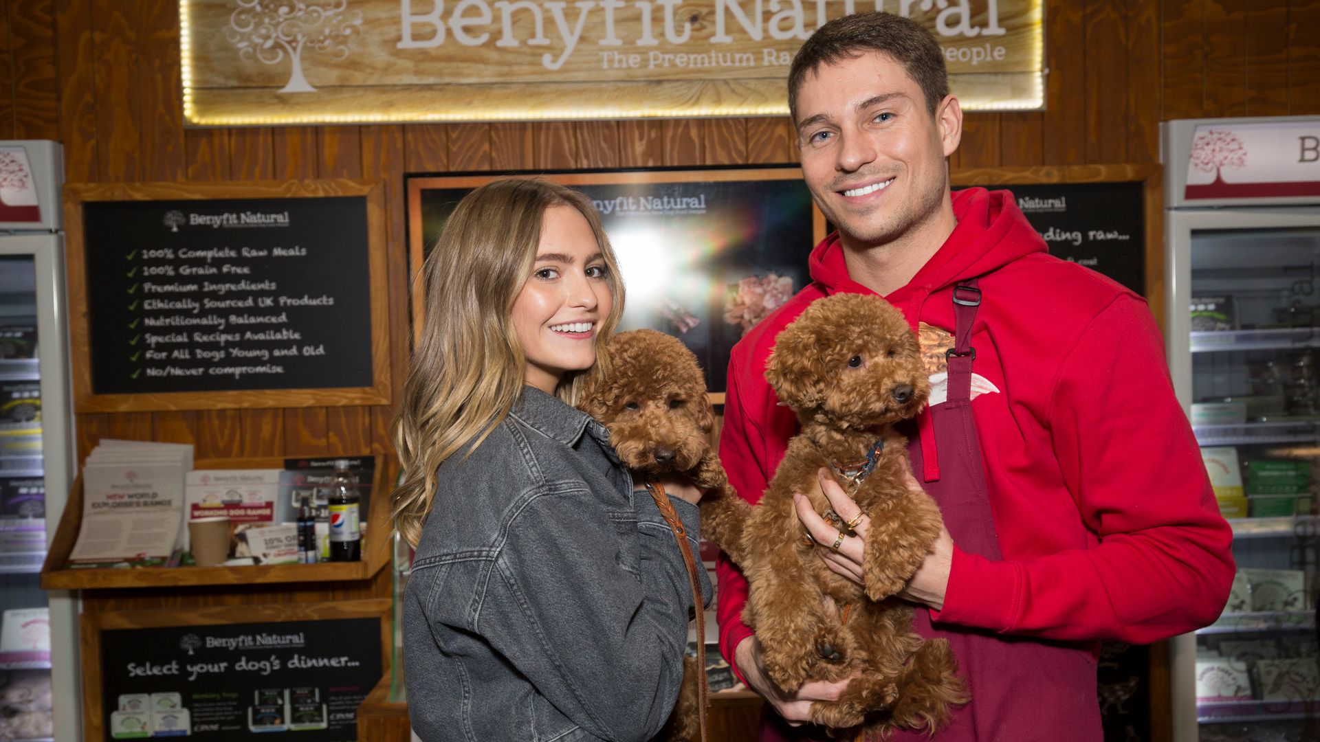 Georgie Purves and Joey Essex carrying brown dogs