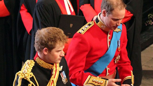 Prince Harry in his black military uniform and Prince William in his red military uniform