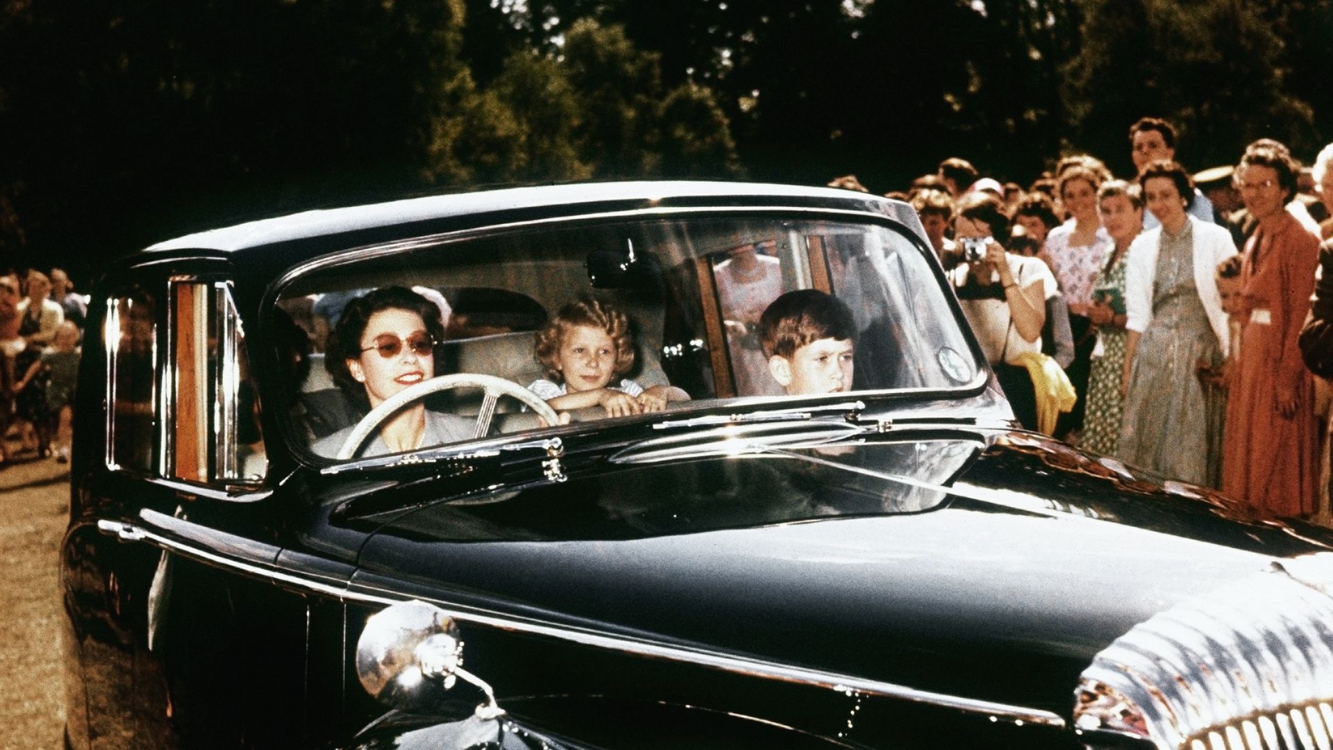 The late Queen in a vintage car with a young Prince Charles and Princess Anne