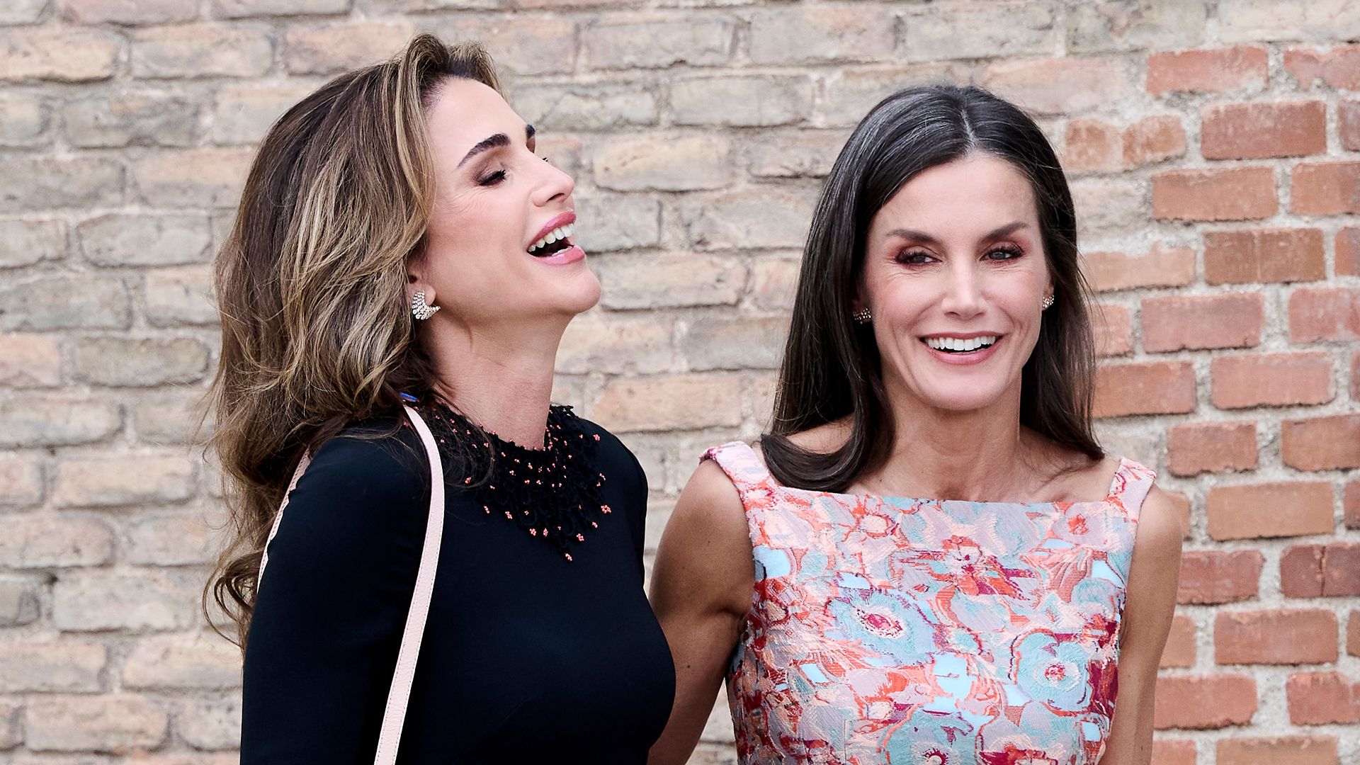 Queen Rania laughs as she puts arm around Queen Letizia
