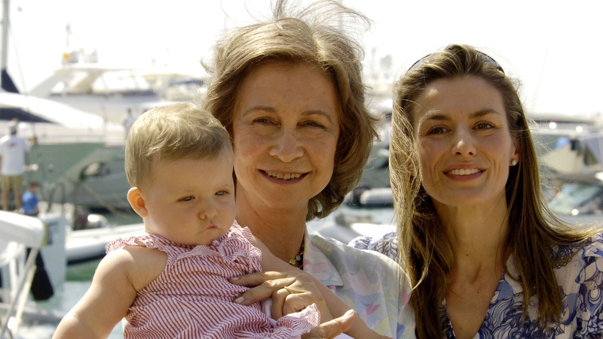 Queen Sofia holding a young Princess Leonor with Queen Letizia in the background