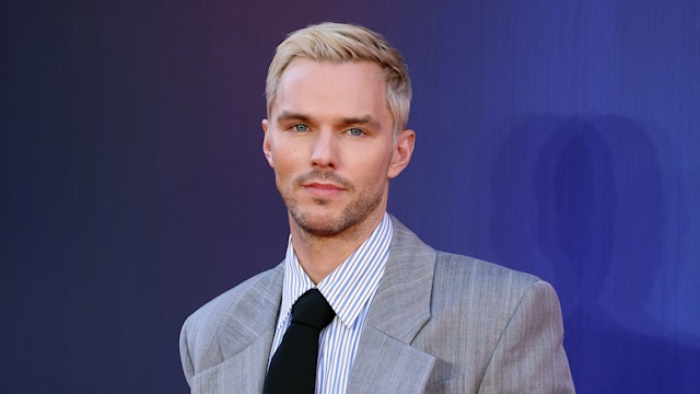 photo of nicholas hoult wearing grey suit and black tie with blonde hair
