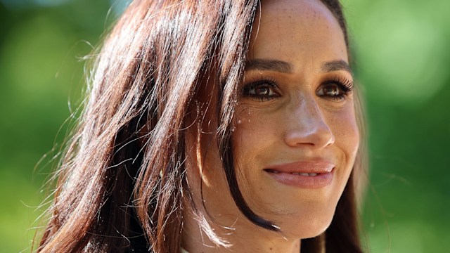 Meghan Markle smiling in a white jacket 