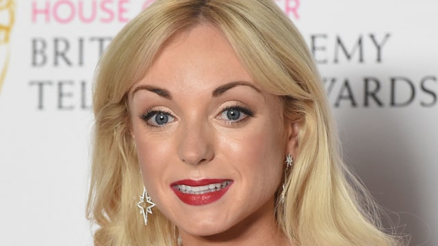 Helen George smiling in a white dress