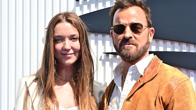 Nicole Bloom in a white blazer and skirt next to Justin Theroux in a suede jacket and sunglasses