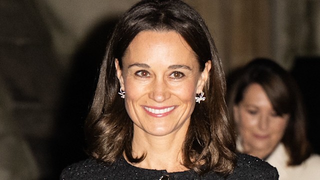 Pippa Middleton smiling in a black coat and red heels