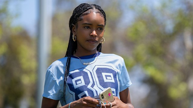 young woman in blue top holding phone and headphones