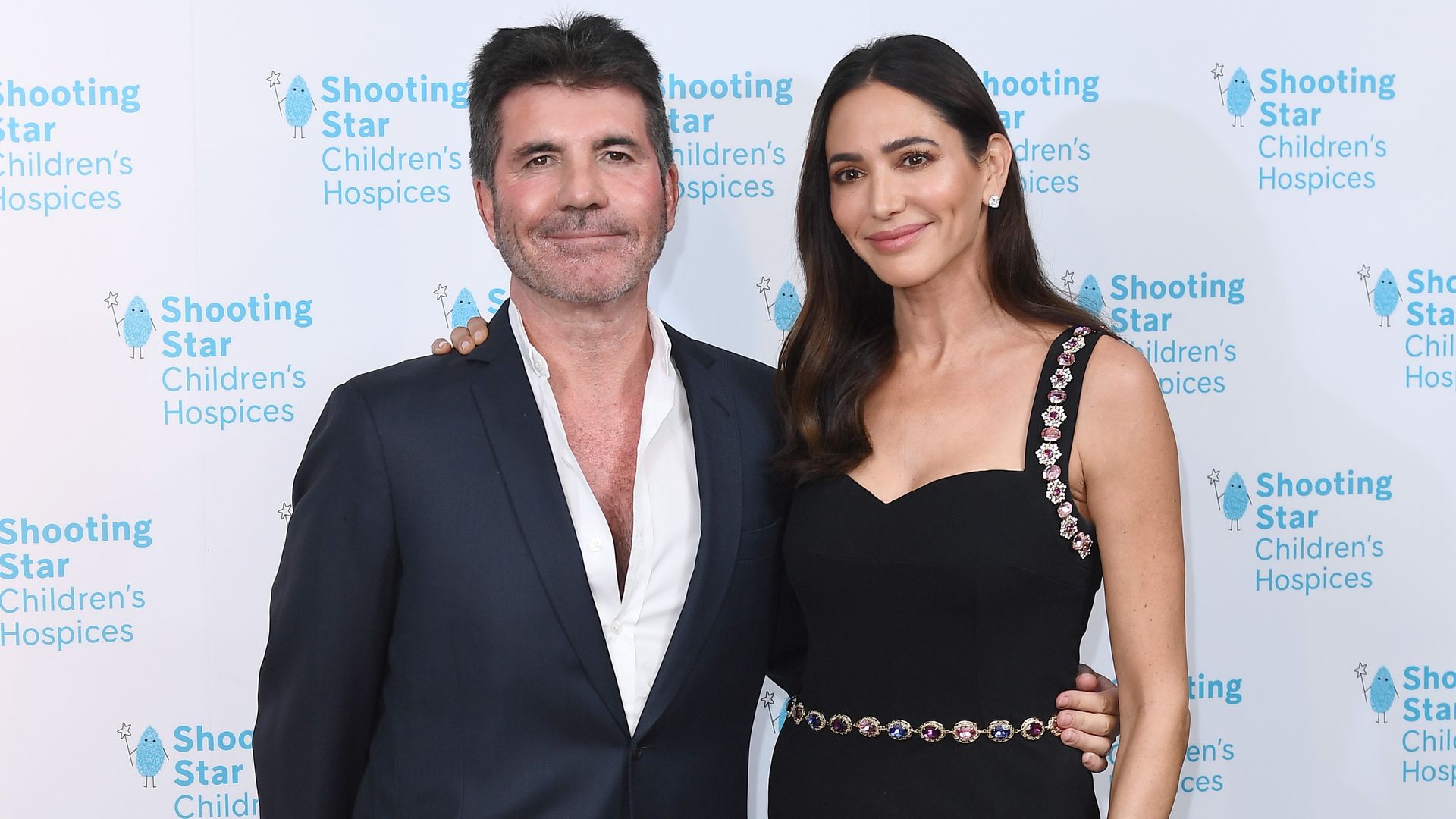 Simon Cowell and Lauren Silverman posing on a red carpet smiling