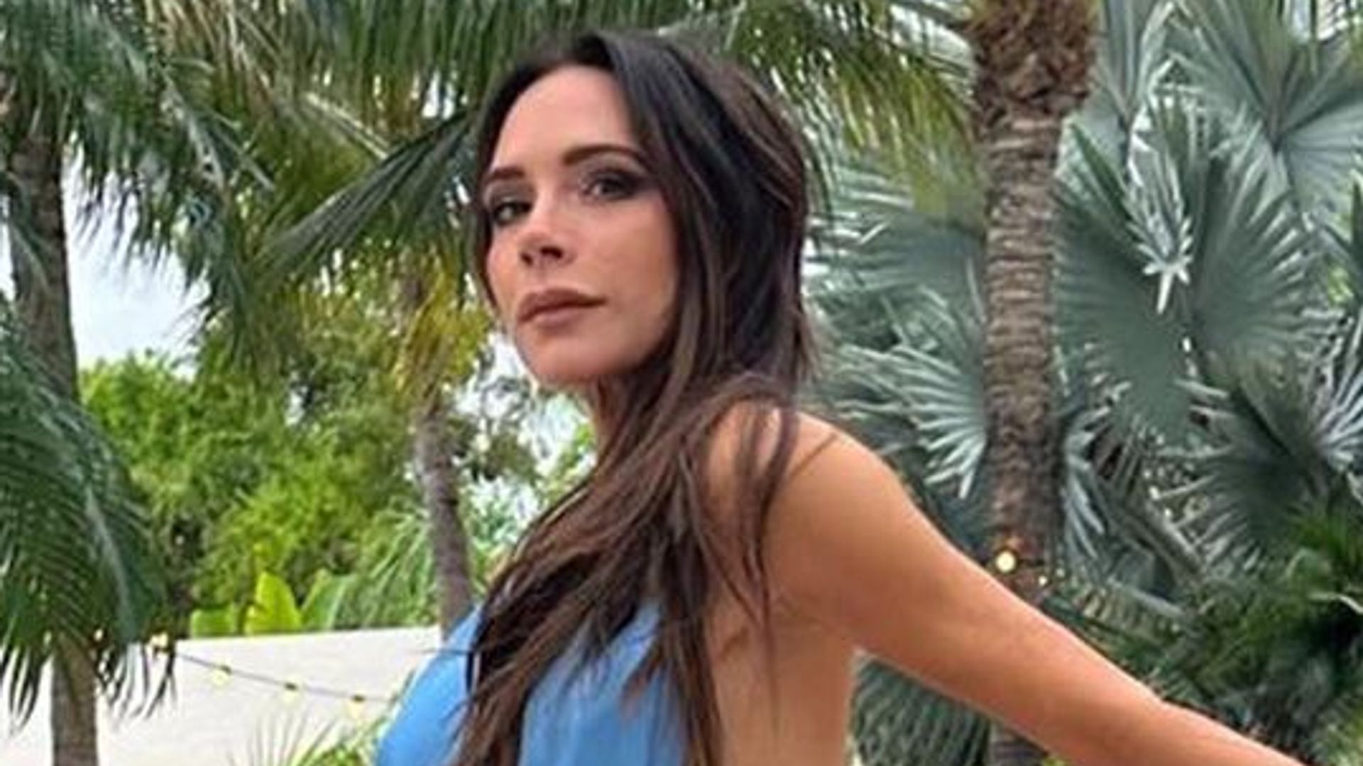victoria beckham wearing blue dress with red train by swimming pool