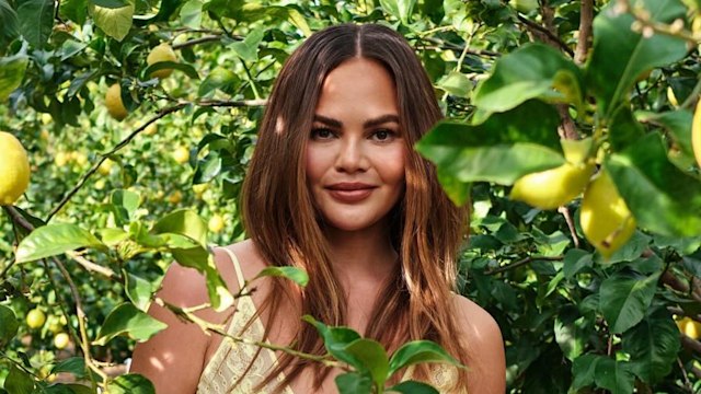 Chrissy Teigen posing in lemon tree in summer outfit 