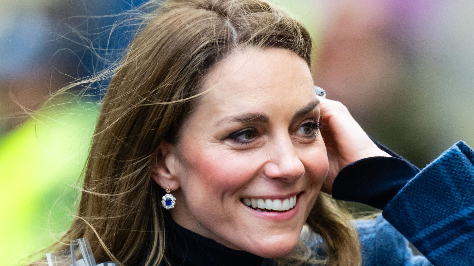 Catherine, Princess of Wales with hand in hair wearing blue coat