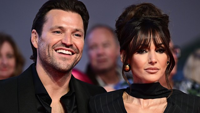 Mark Wright smiling next to straight-faced Michelle Keegan
