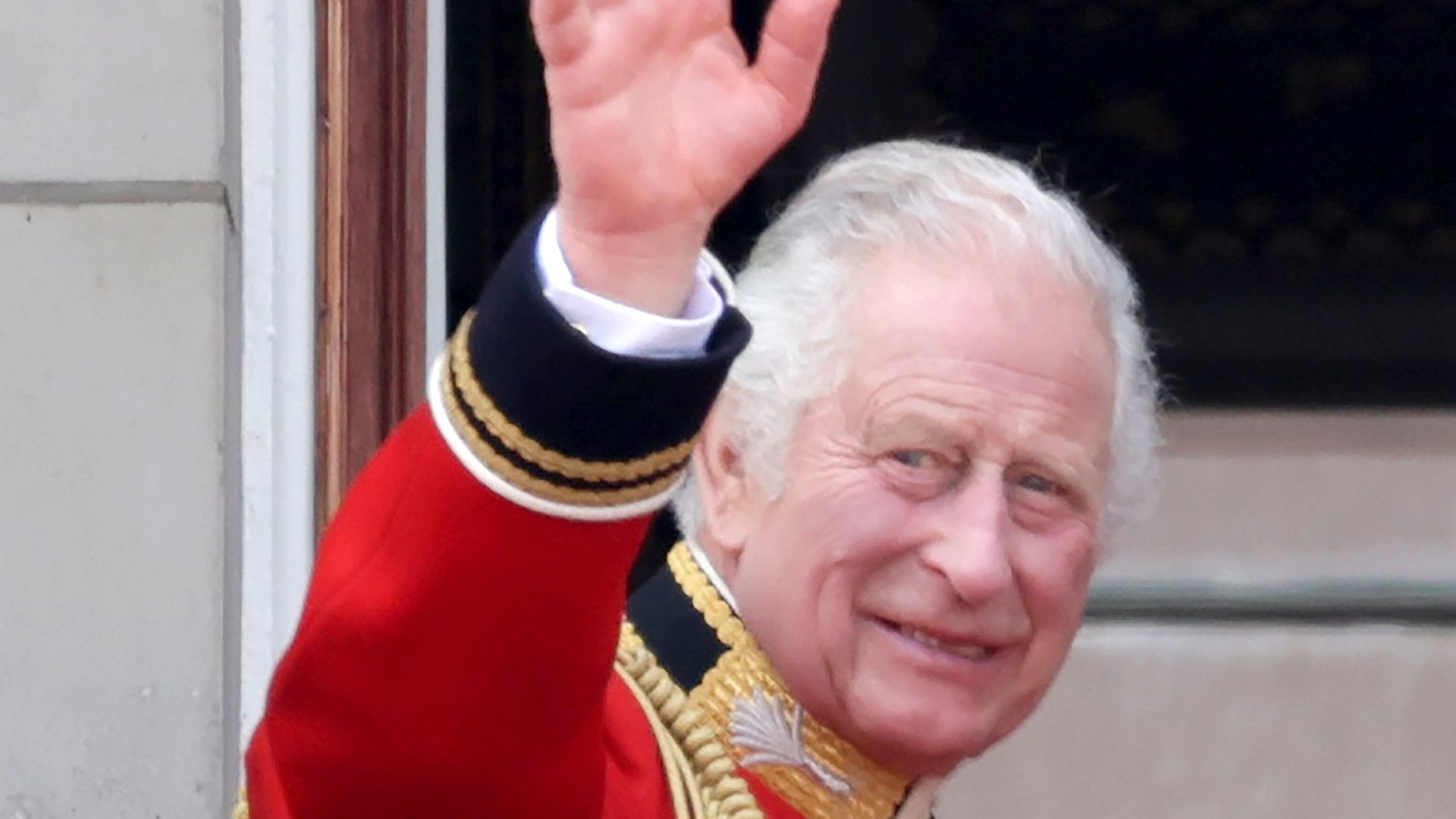 King Charles in ceremonial outfit waving at crowds