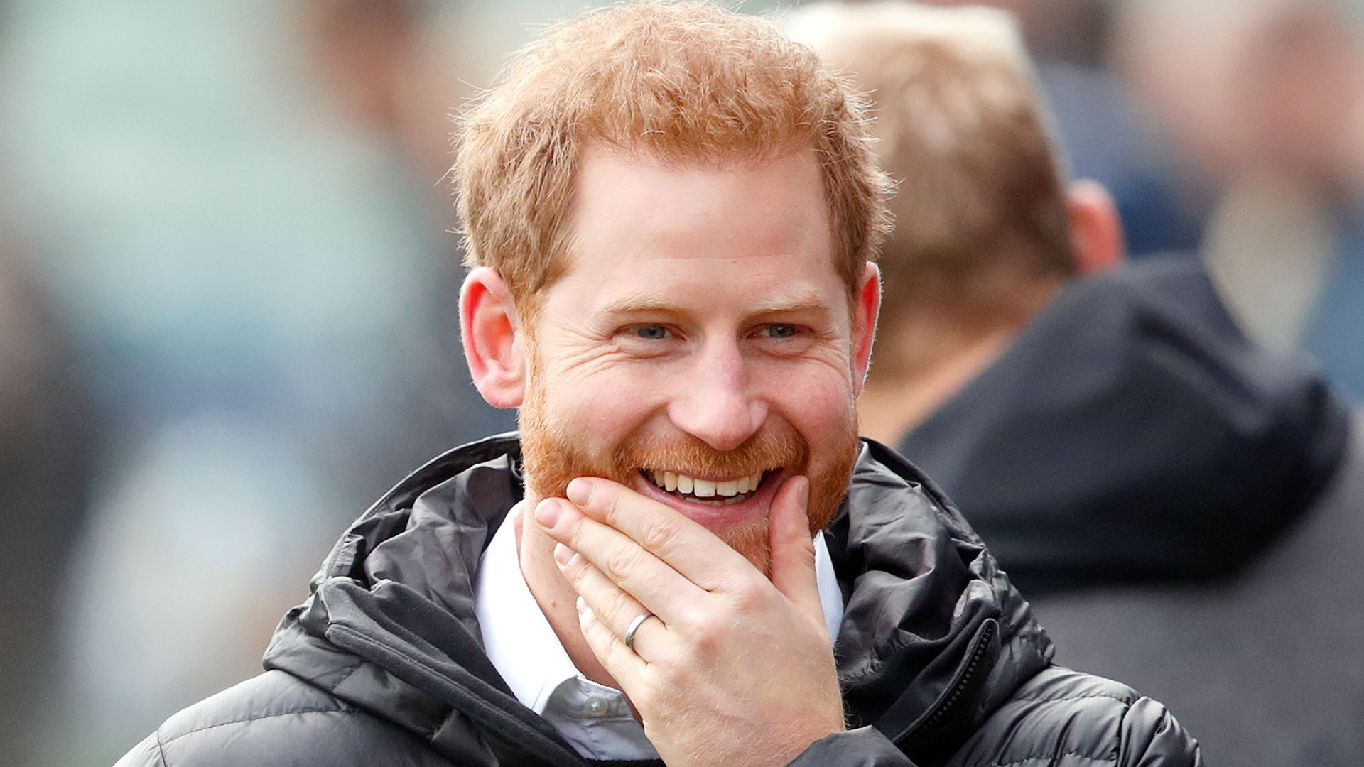 Prince Harry smiling wearing a puffer jacket