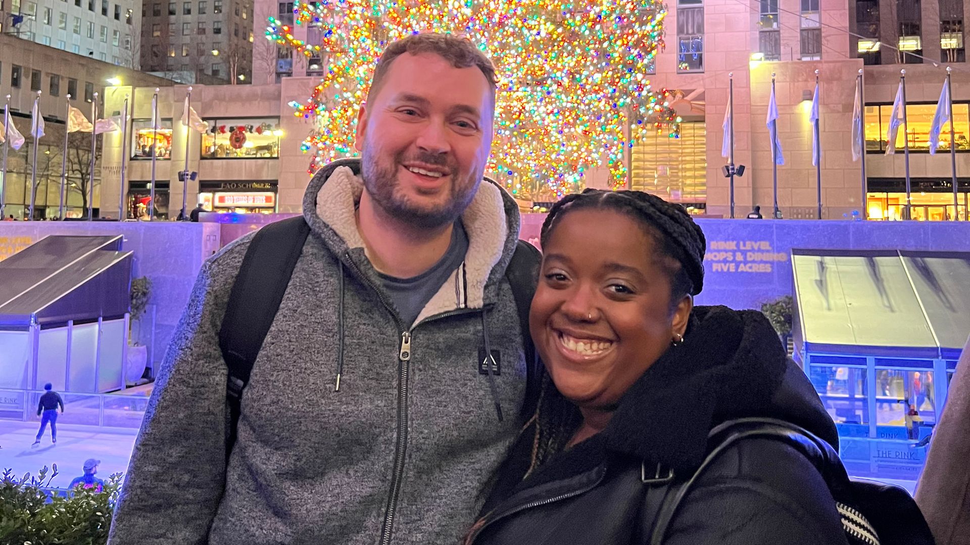 Young man and woman smiling in New York in front of a Christmas tree