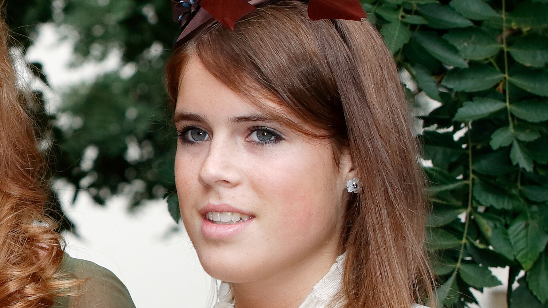 Princess Eugenie in a white dress and brown fascinator
