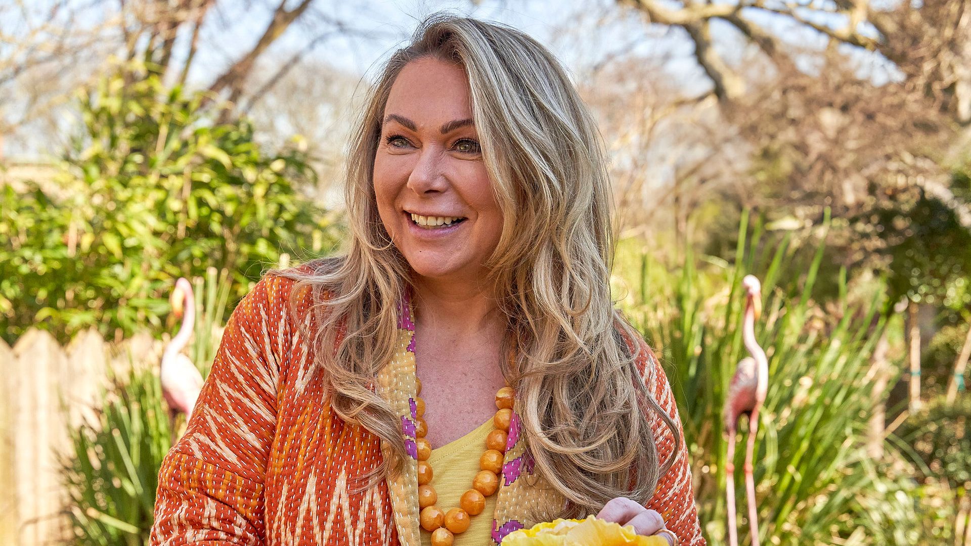Woman in orange pruning yellow flowers