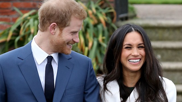 Prince Harry looks at Meghan Markle as she laughs in a white coat