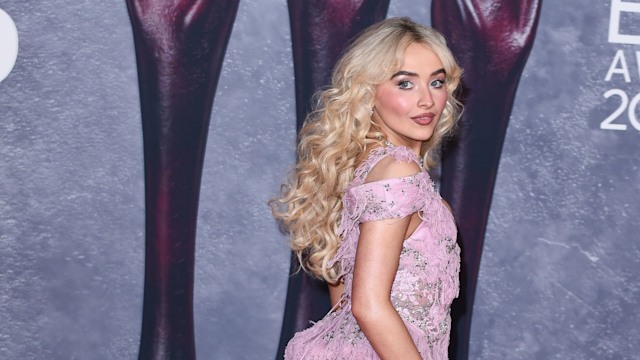 Sabrina Carpenter looking over her shoulder in a pink dress