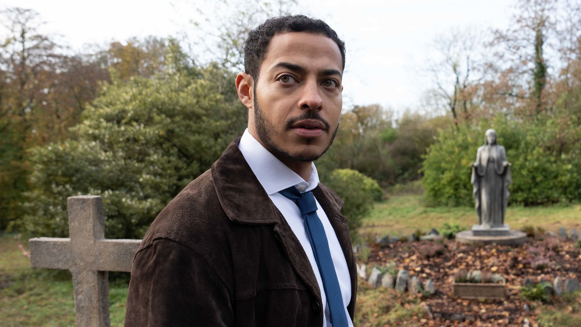 MAN IN SUIT STANDING IN GRAVEYARD