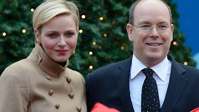 Princess Charlene in a cream coat with red lipstick next to Prince Albert