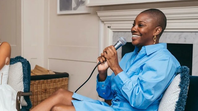 Yomi Adegoke sits in a blue chair with a microphone