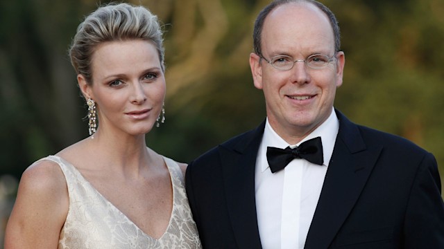 Princess Charlene of Monaco in a cream dress with drop earrings next to husband Prince Albert II 