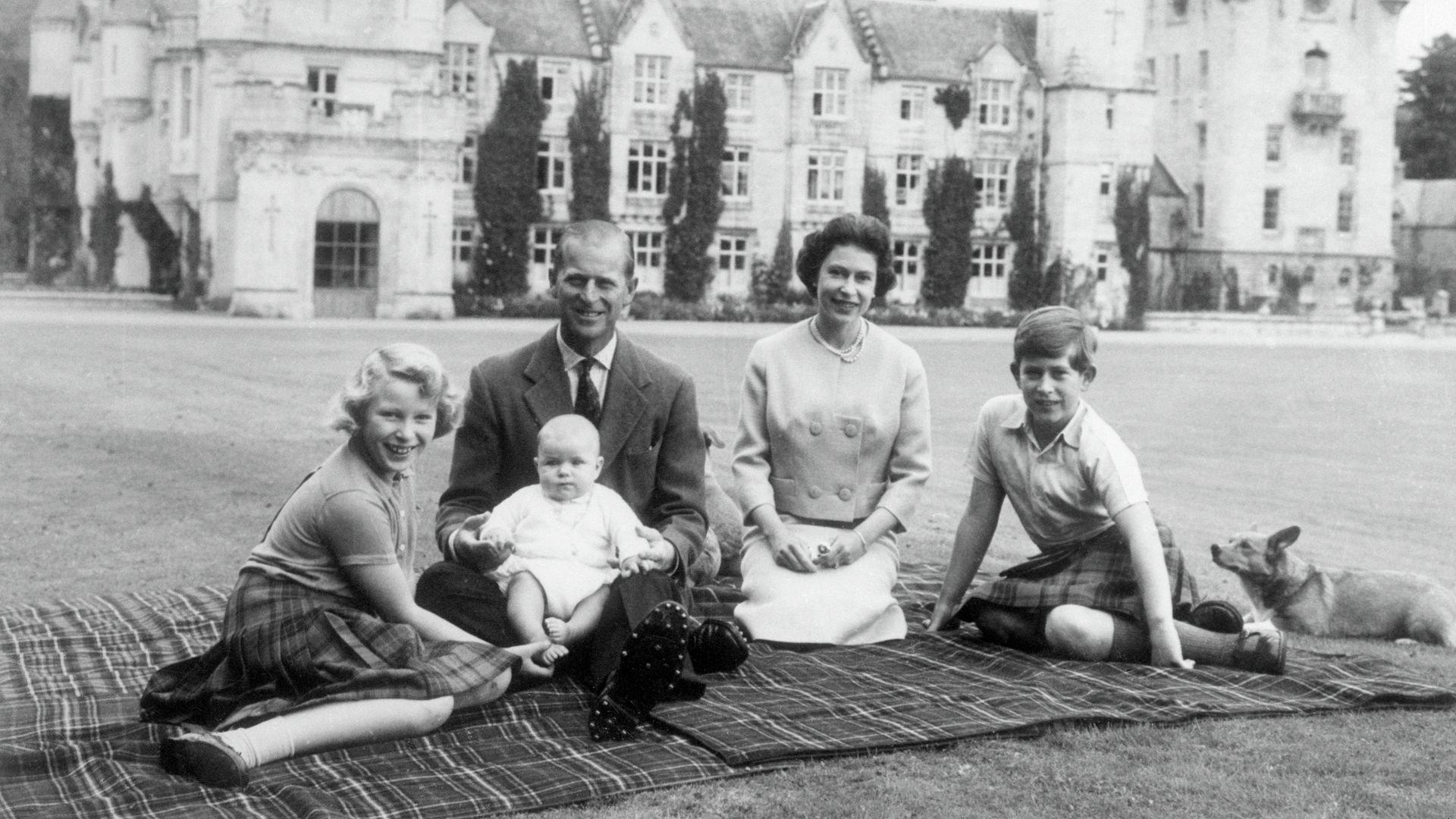 A black-and-white photograph the Queen and Prince Philip with a corgi and a young Princess Anne, Prince Andrew and King Charles